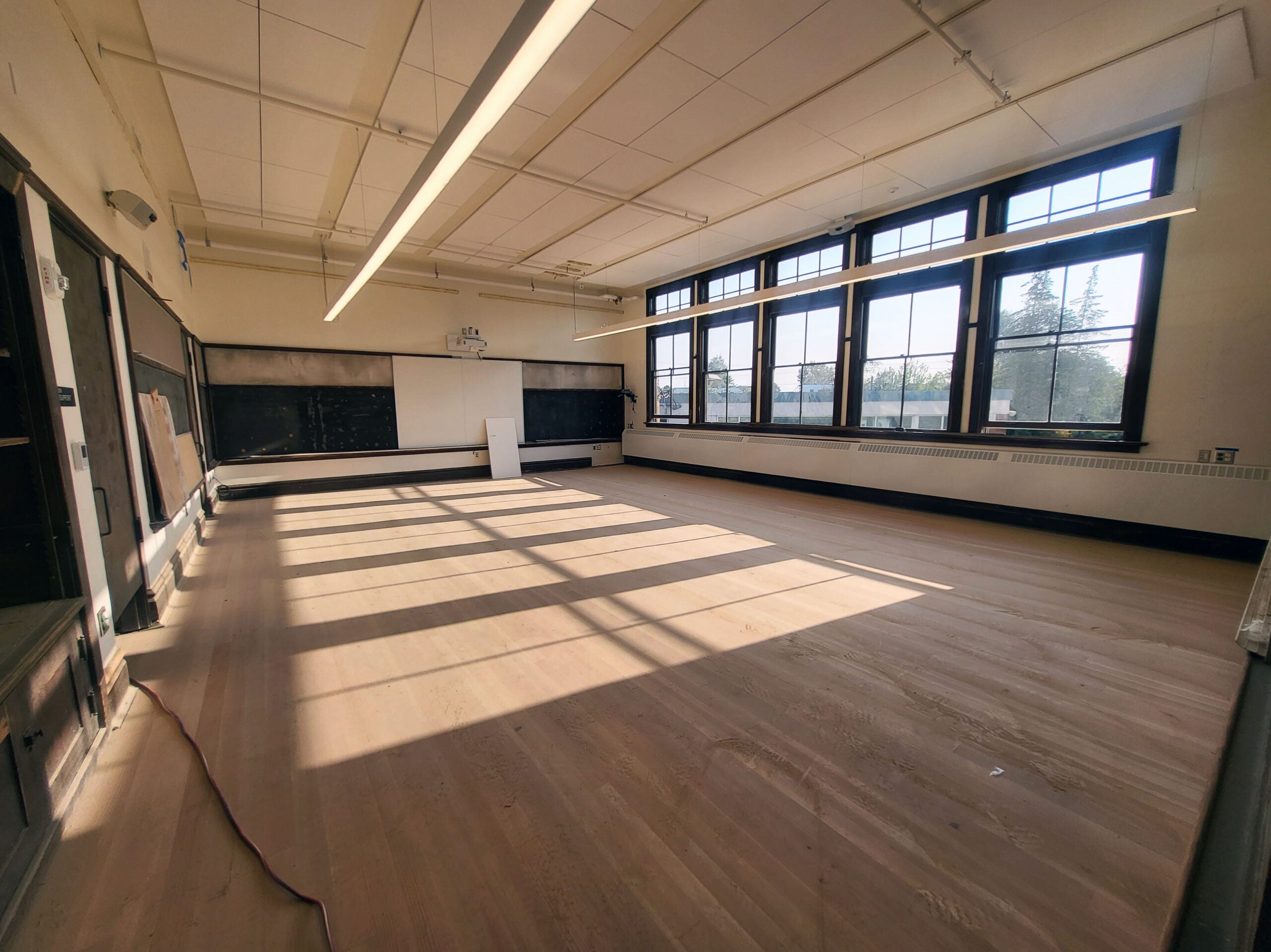 a classroom with a wood floor and wood framed windows