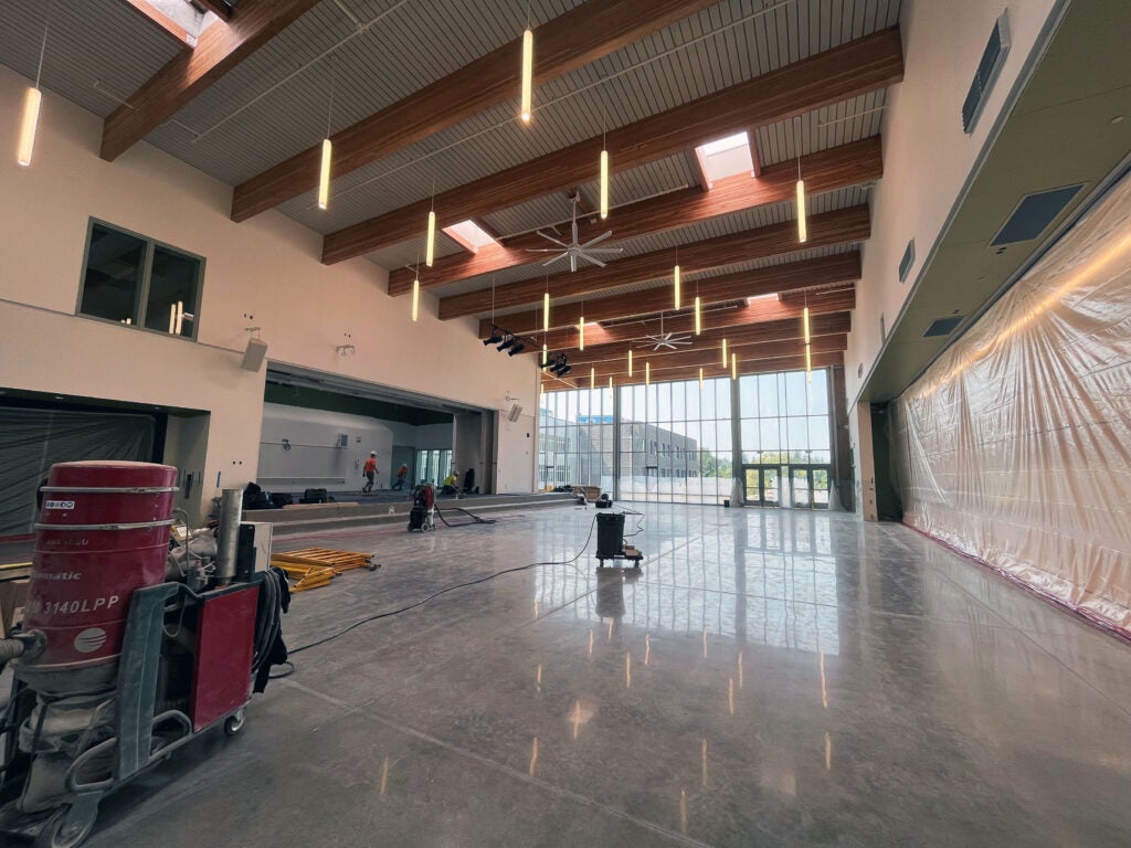 a large room with a stage has a wall of windows looking outside