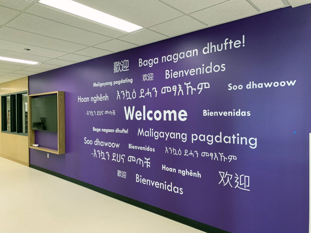 a purple wall has the word Welcome in multiple languages