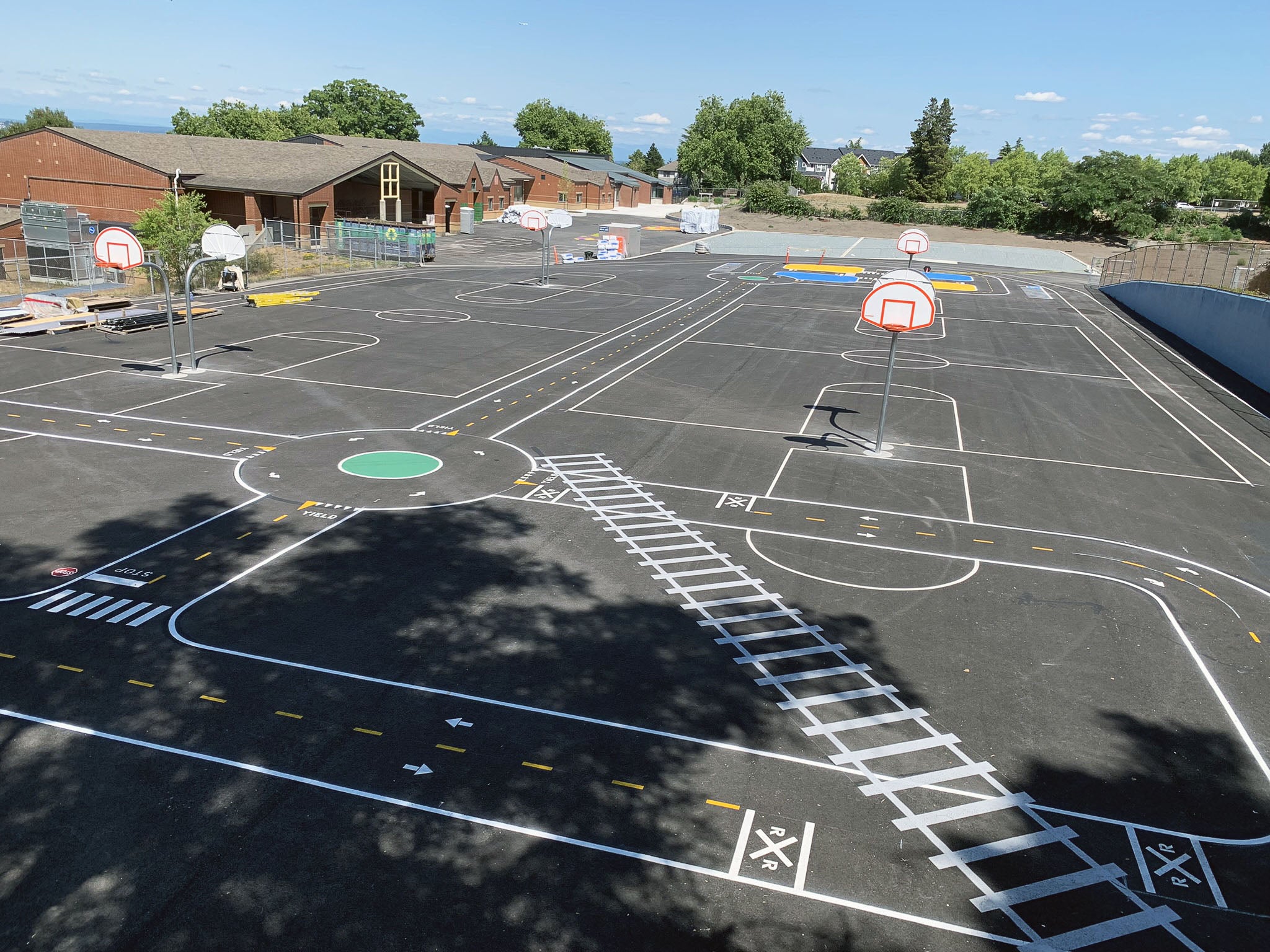 a paved area has lines for baskeball and basketball hoops, plus painted bike traffic lines