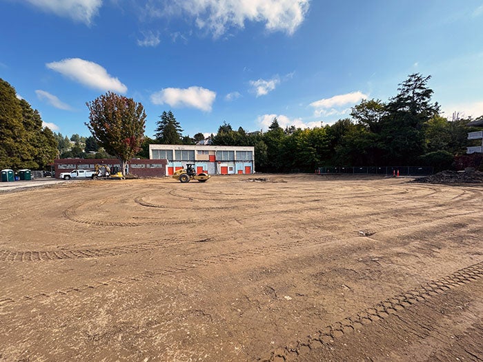 a graded dirt field in front of a two story building