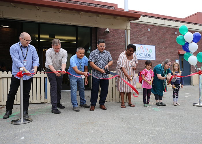 a group of people hold scissors and have just cut a red ribbon