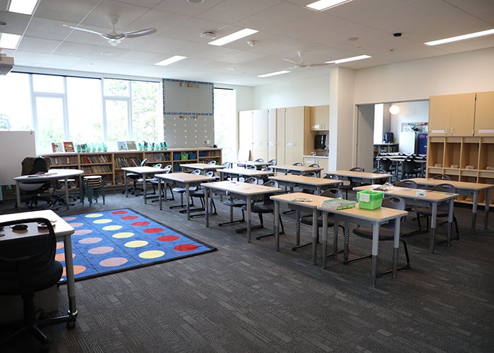 a classroom with desks in rows and an area rug with colored circles