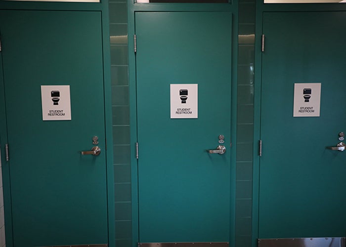 3 teal-colored doors have a toilet icon and say student restroom