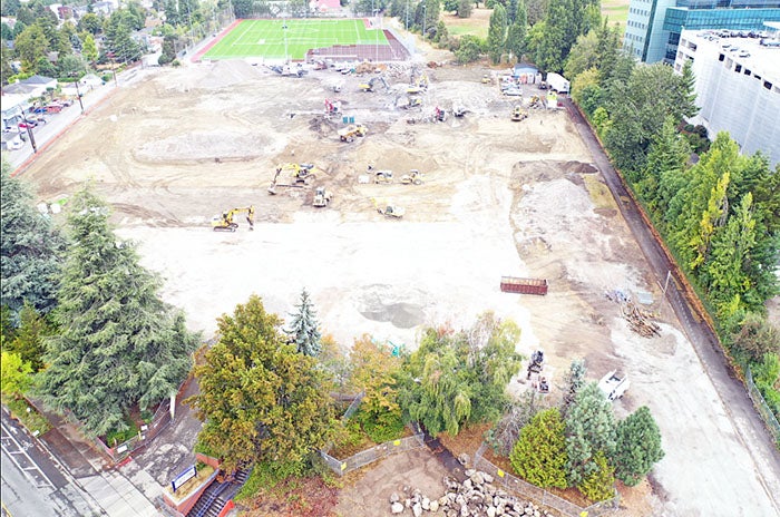 a construction site with construction equipment and trees