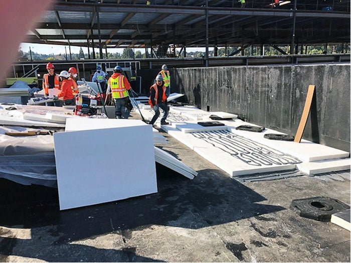 A group of men in orange vests and helmets working on a construction site