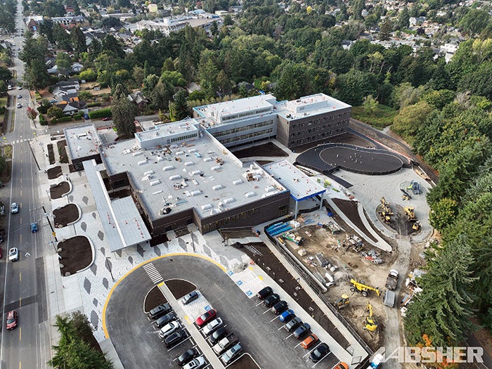 aerial view of a large building with a parking lot and trees