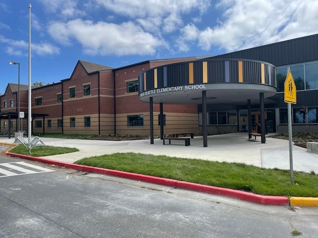 a two story brick building has a circular entry canopy with colored panels