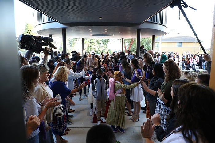 a crowd of people includes children and adults and are moving toward the camera