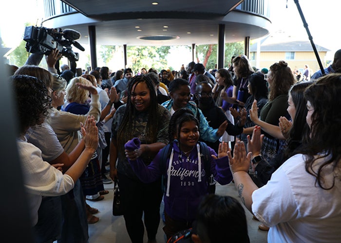 a crowd of people includes children and adults and are moving toward the camera