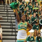 Two cheerleaders in Roosevelt school colors of green and gold lead a crowd in cheer