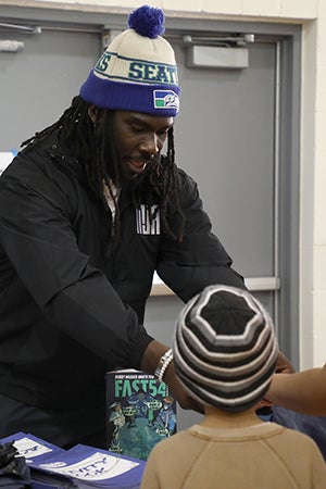 Myles Adams helps hand out coats and warm gear to students in a gym