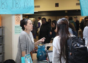A student and professional talk together at a table during a career day event.
