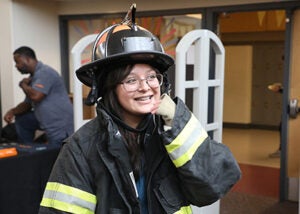 A student tries on a firefighter coat and hat during career day event.