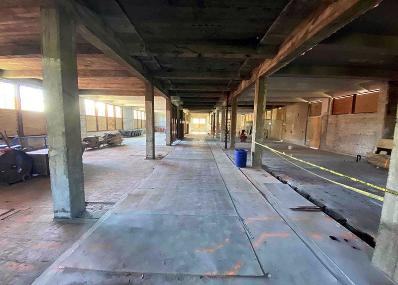 inside of a building partially torn up with posts and beams with some windows covered in wood and some open