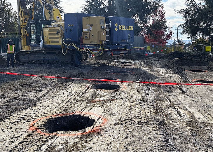 a large construction machine is on a field of soil that has large round holes in it