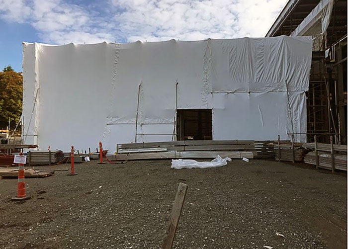 A building is wrapped in white material with a hole for a door.