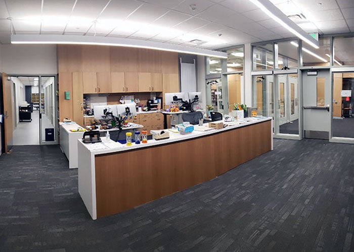 an office with a reception desk and full height glass windows