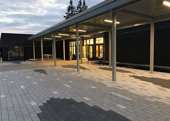 a breezeway in front of a building with glass doors and decorative pavers