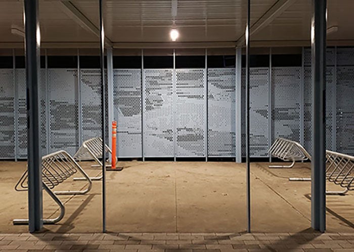 a covered area with bike racks and a perforated metal back wall