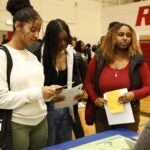 Students read and listen to more information at a booth at the Black College Expo