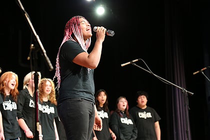 Student with pink braids sings a solo during a choir concert