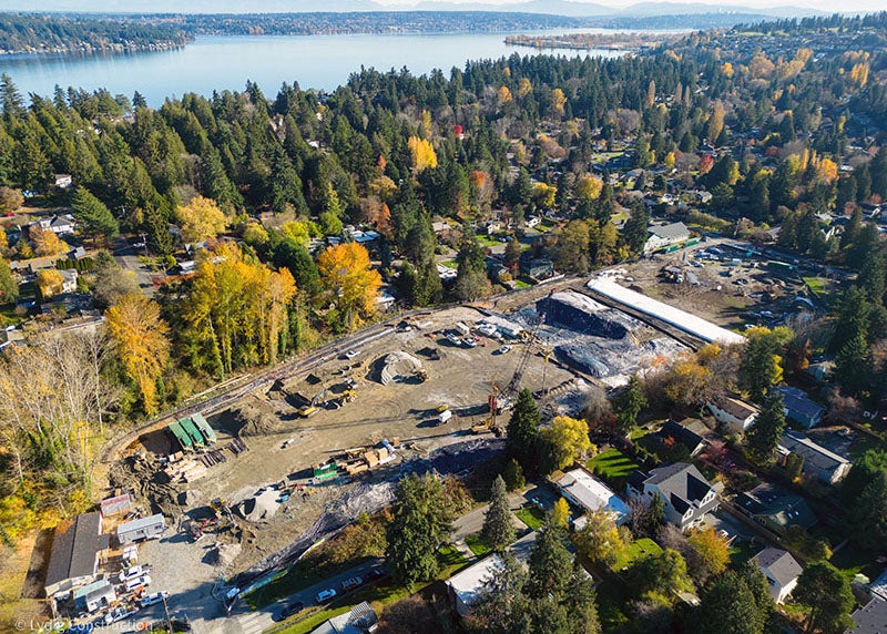 aerial view of a construction site surrounded by trees and houses