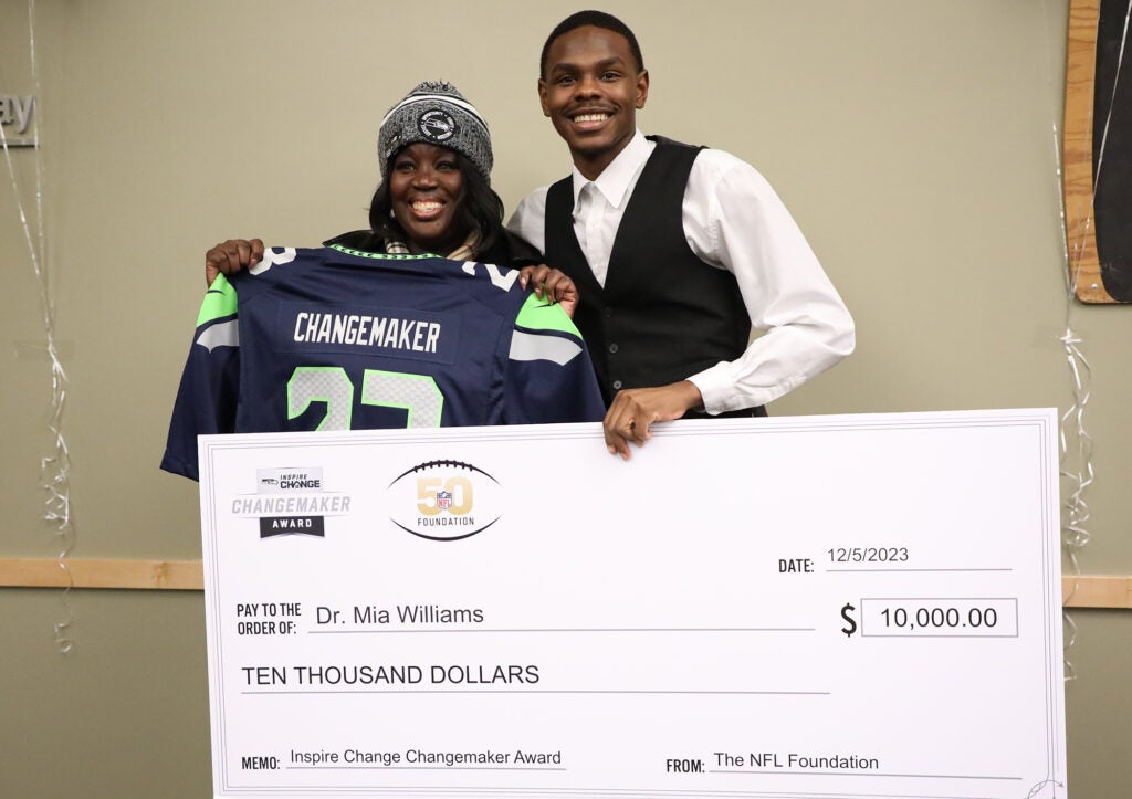 Dr. Mia Williams and student hold a giant $10,000 check awarded by NFL Changemaker.