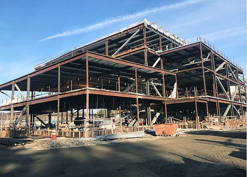 a four-story steel frame rises above the soil at a construction site