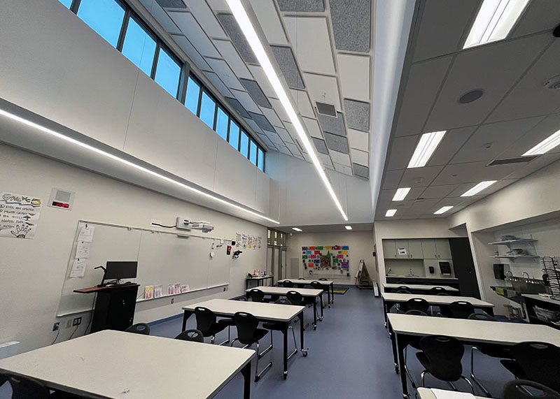 a large clasroom has tables and a white board with transom windows and ceiling lights