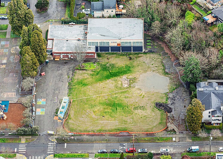 Aerial view of a large lot with ponding and grass next to a building