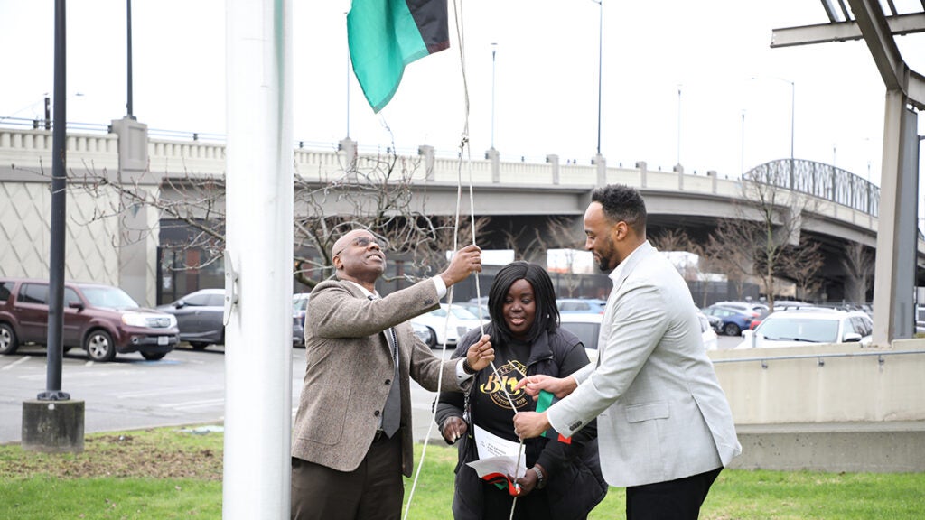 Superintendent Jones, Dr. Williams, and Dr. Jackson work together to raise the flag.