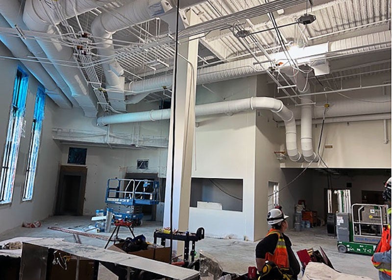 a two story interior space under construction with large pipes in the ceiling