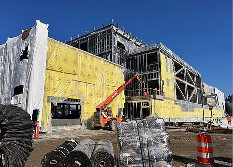 exterior of a 2, 3, and 4 story building under construction with materials in the foreground