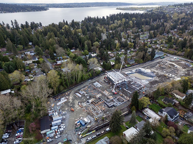 aerial of a large construction project with a crane, equipment, and mud. there is a lake in the distance