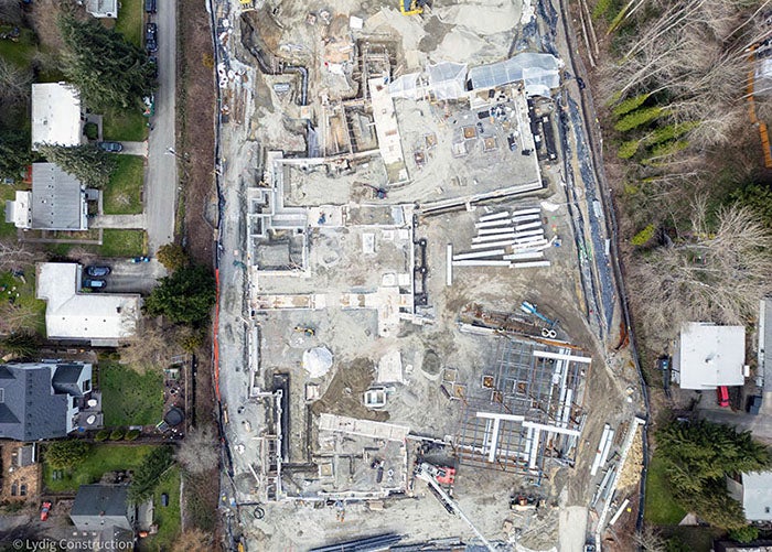 aerial of part of a construction site with foundations outlining the building footprint and some structural steel erected