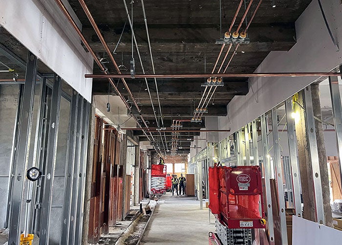 metal framing and wallboard in a hallway with copper pipes running across the ceiling space