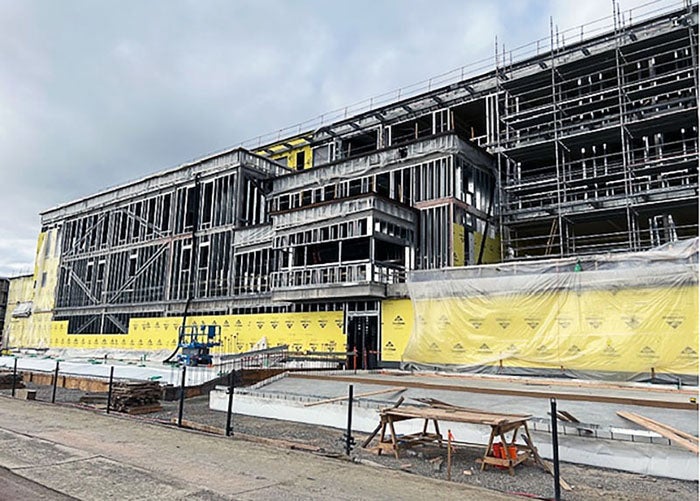 a 4-story building under construction has metal framing and the bottom floor has yellow sheathing