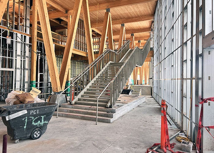 a steel interior stairway inext two a framed in wall on one side and large laminate beams on the other side