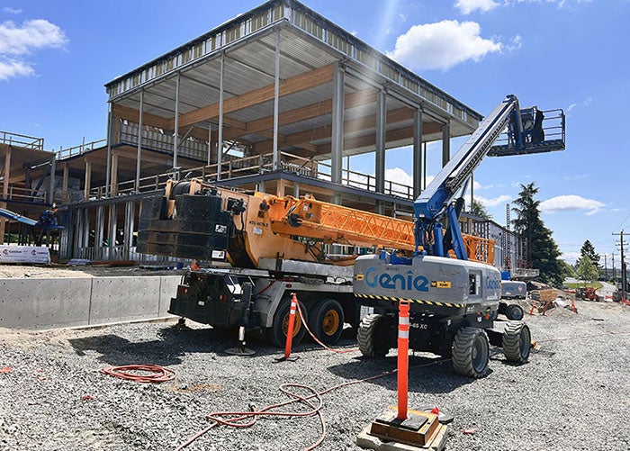 exterior of a partially built wing of a building withe a roof and construction equipment