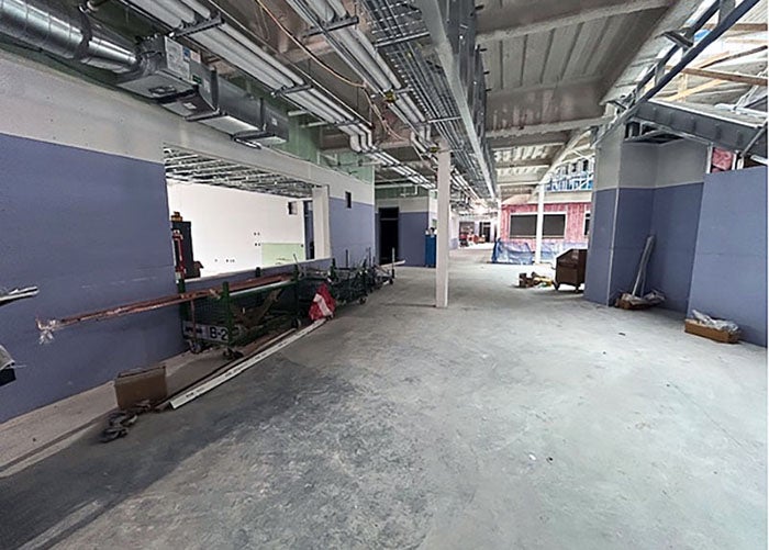 a hallway under construction has utility runs in ceiling and wall board being placed on walls