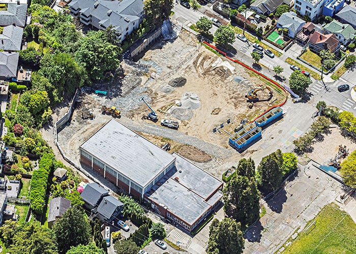 aerial photo of a building with a construction area in front of it including equipment and piles of gravel