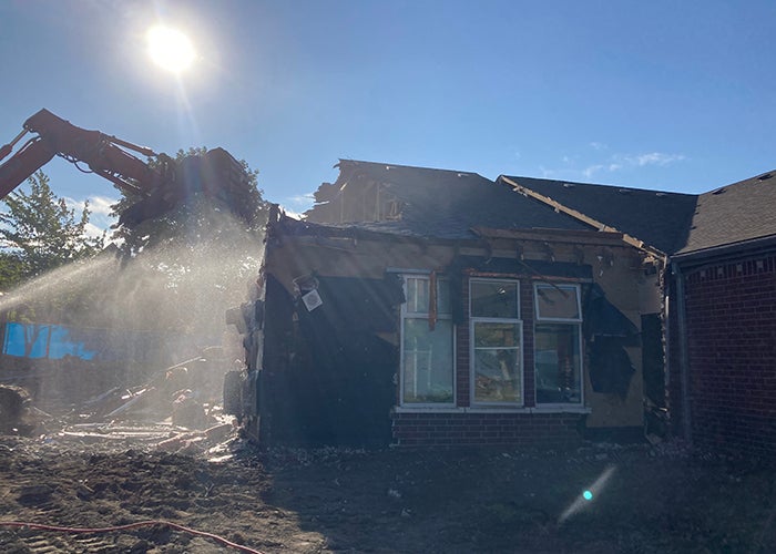 a loader is demolishing part of a brick building