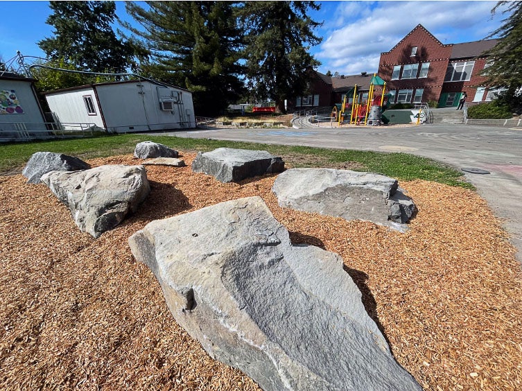 A group of large boulders set into the ground with bark around them