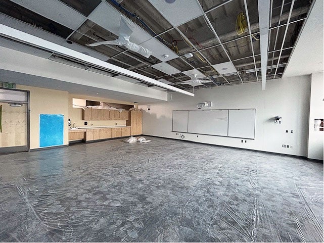 a large space with cabinetry and a white board and a ceiling grid
