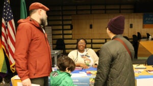 Two people and a child speak with an SPS staff member at the Admissions Fair