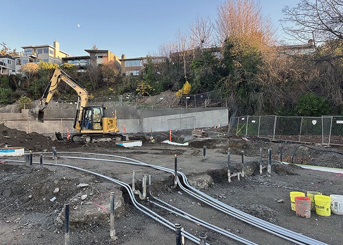 conduit running across dirt with pipes sticking up and construction equipment