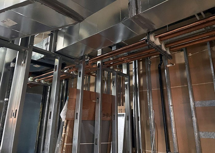 copper pipes and silver ductwork in a space under construction