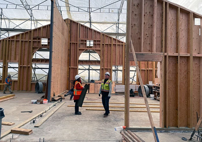 two people in a space with partially framed walls with a plastic tent roof