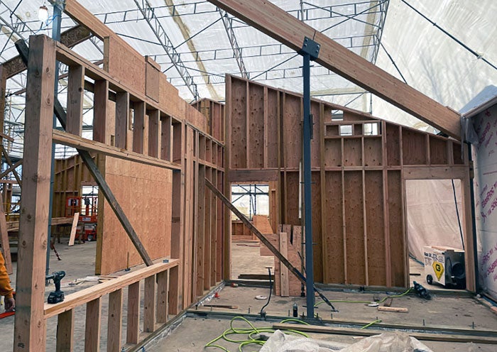 framed walls with a plastic tent on scaffolding above